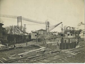 Historical photograph of a construction site in 1930 where power lines are prominently featured.