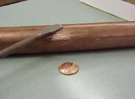 example of a copper pipe next to a shiny penny