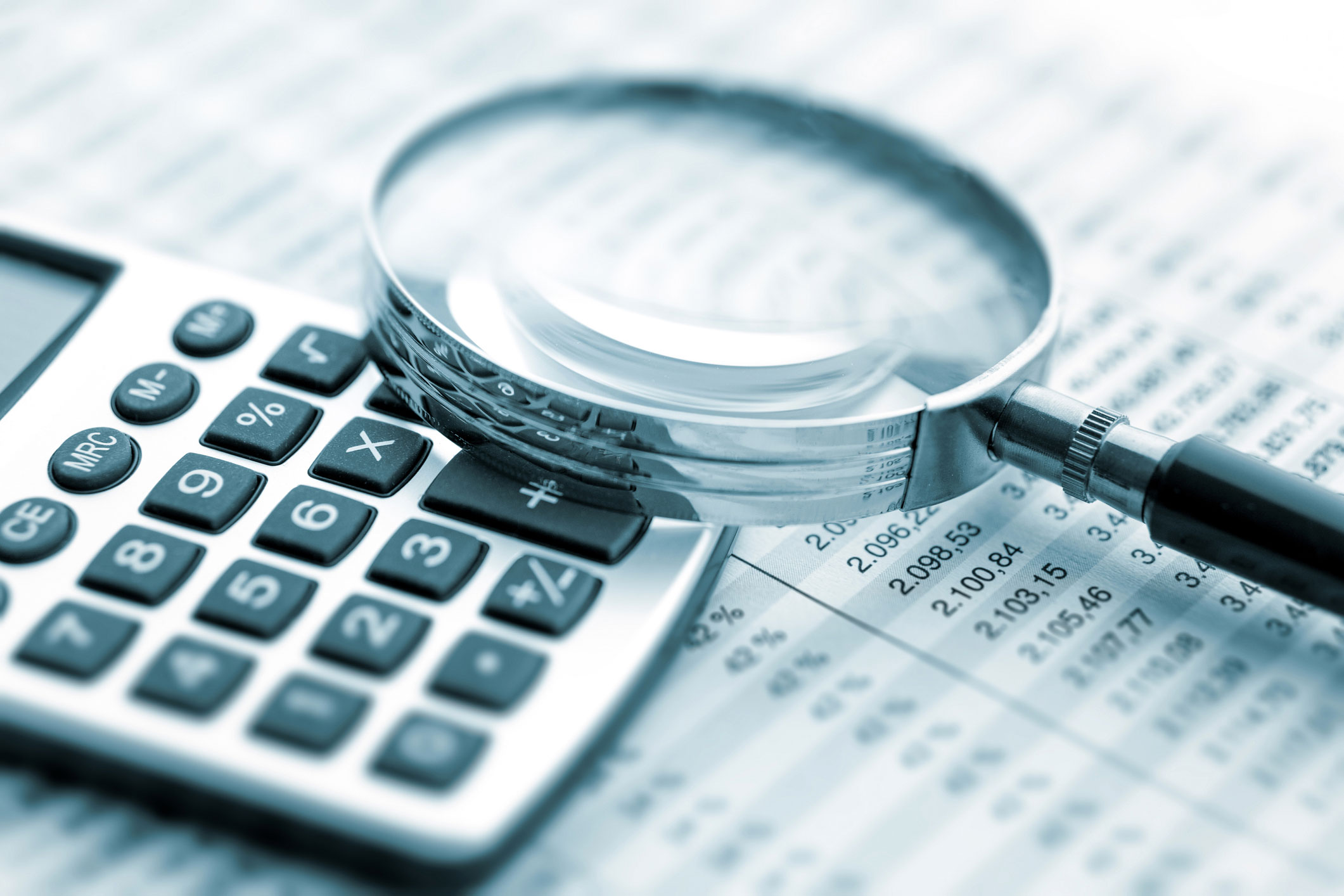 magnifying glass and calculator on a finance ledger