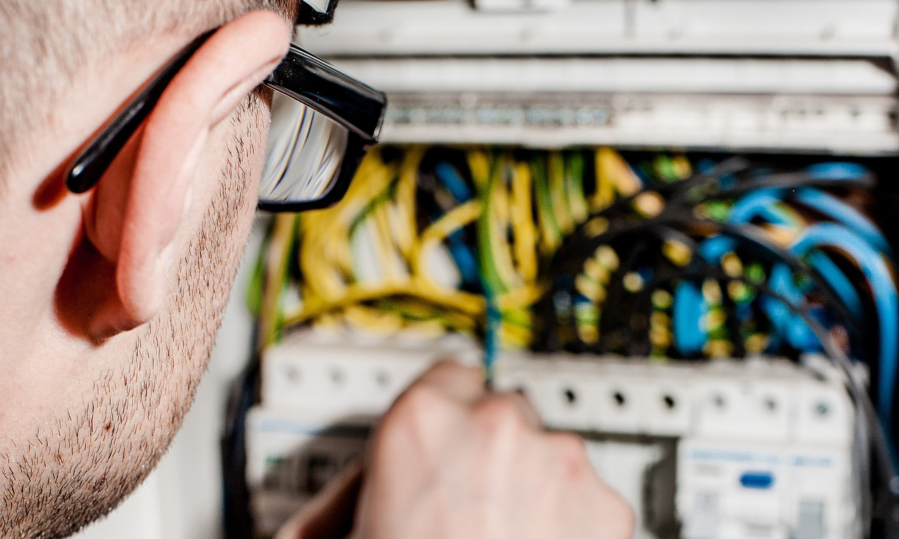 Electrician working on a box on a wall with lots of wires