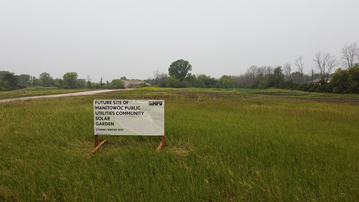 A sign in a field announcing the spot for a future community solar power project