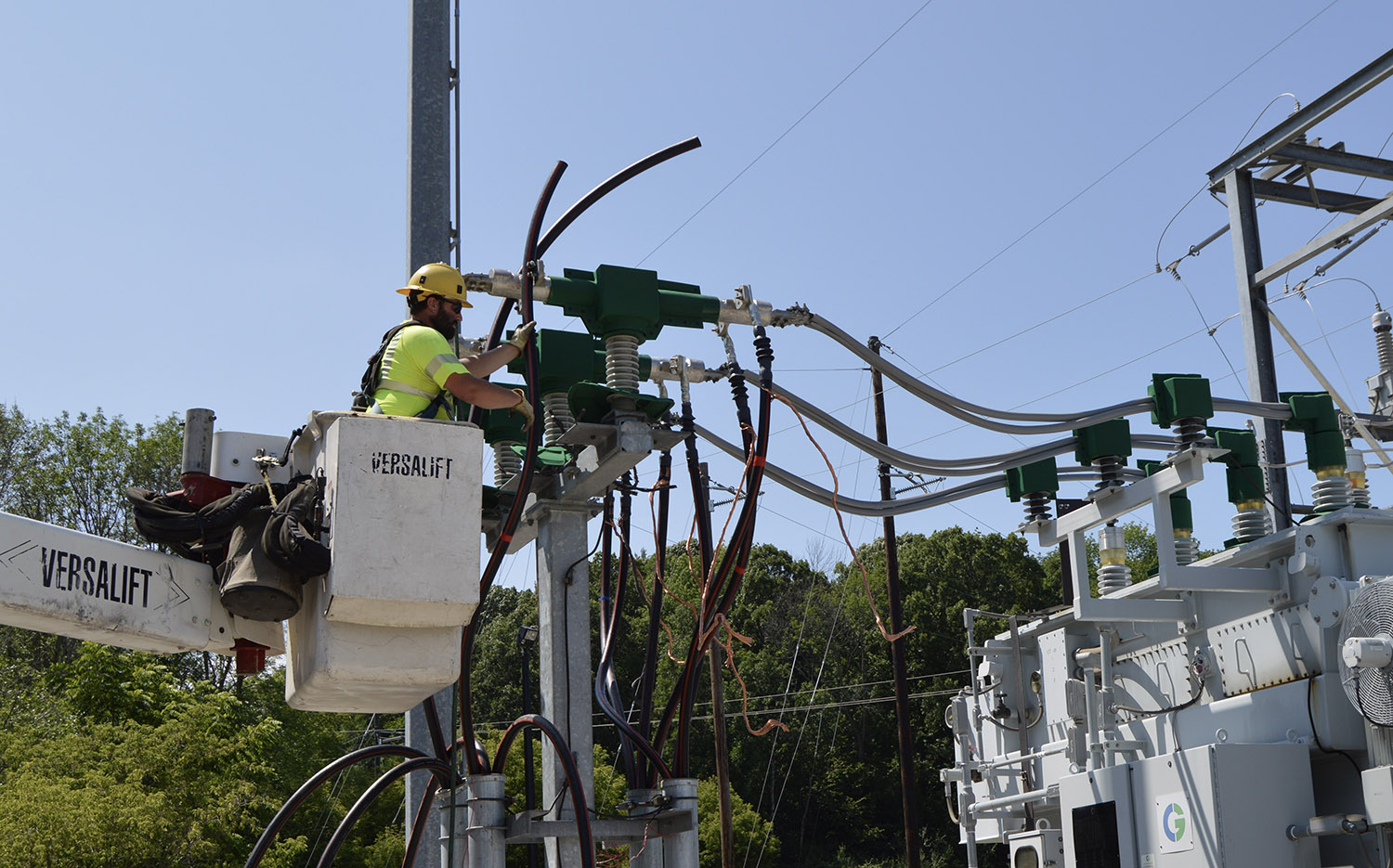 An electric worker in a cherry picker working on some electrical equipment