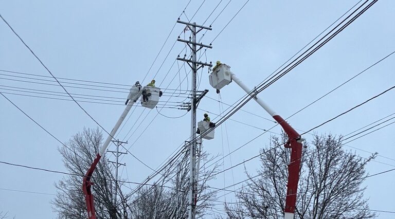 three bucket trucks working on power lines to restore power